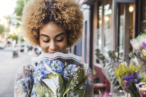a young woman holding a bouquet of fresh cut flowers on a sidewalk