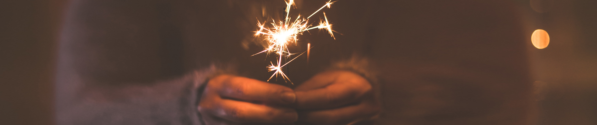 a lit sparkler being held along with the moon lighting the sky