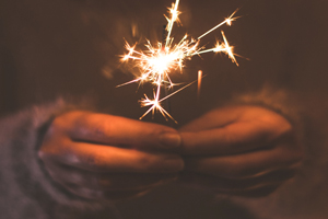 a lit sparkler being held along with the moon lighting the sky