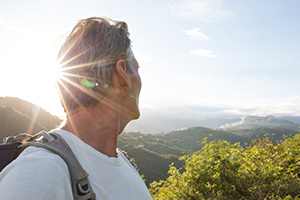 Man with a backpack looking out over a green valley