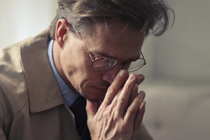 Man in coat sitting thinking