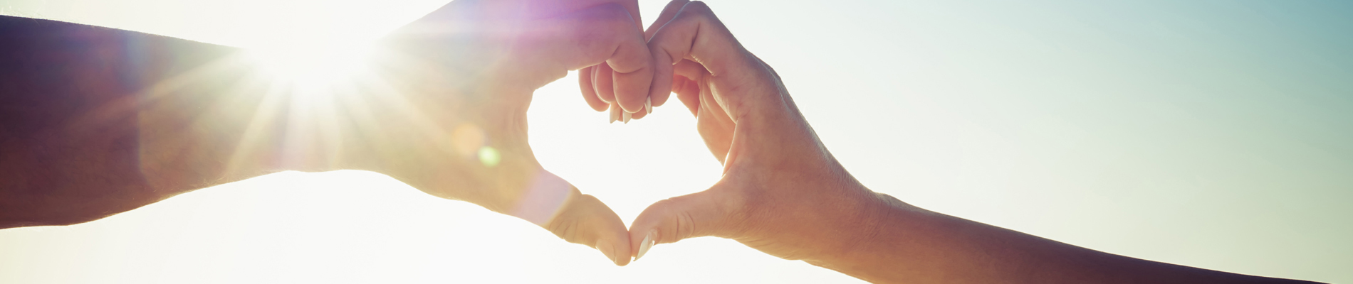 Two hands making a heart symbol towards the sky