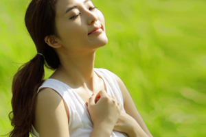 Young lady folder hand on chest in mild of a field