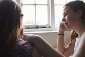 Two women having conversation near windowsill