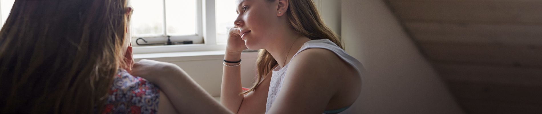 Two women having conversation near window sill