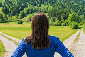 Woman walking down a road approaching an intersection and needing to make a choice