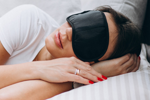 Woman lying on a bed with a sleeping mask on