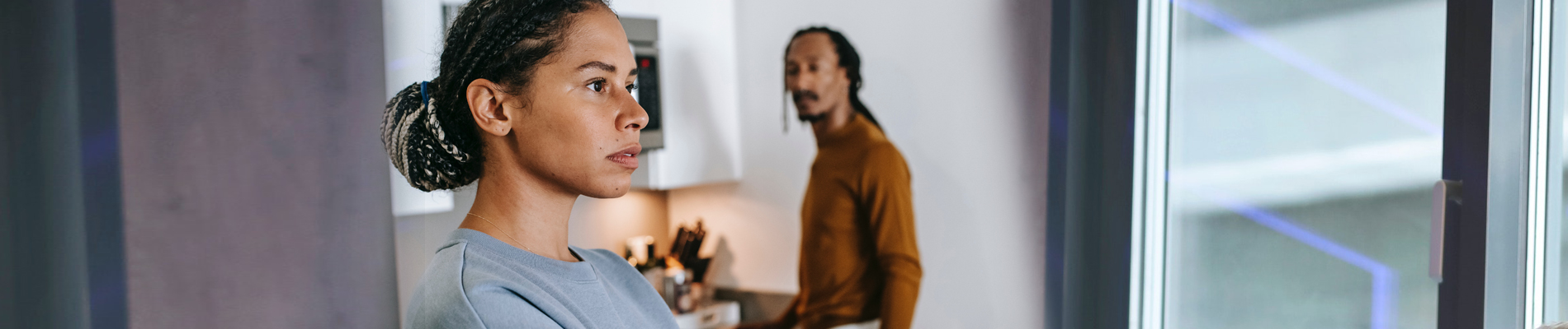 A couple standing apart in the kitchen with lost gaze on faces