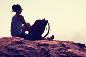 a woman sitting on a rocky bluff looking of into the distance