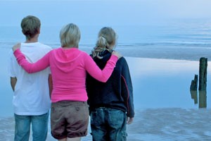 mom with daughter and son on a sandy shore looking out into the ocean