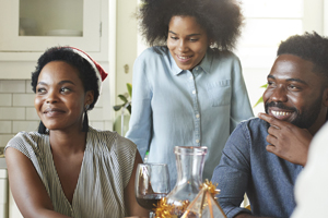 mom, dad, daughter in kitchen with other adults sitting at the table in discussion
