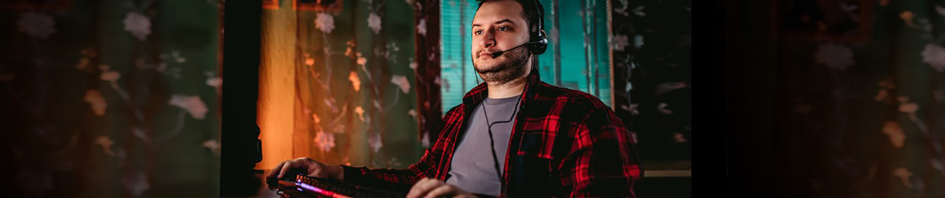 a man sitting with a headset and gaming panel/keyboard in his lap