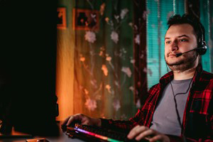 a man sitting with a headset and gaming panel/keyboard in his lap