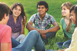 A group of young adults sitting in a circle in a grassy field