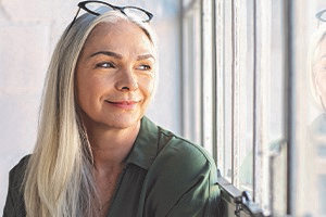 Woman with glasses on her head gazing to the side through a window